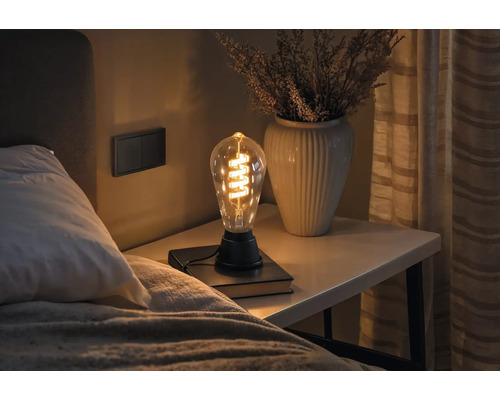 Lampe décorative Edison sur une table de chevet à côté d''un lit.