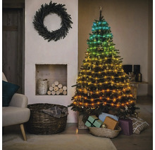 Dekorierter Weihnachtsbaum mit Lichterkette neben Kamin und Kranz