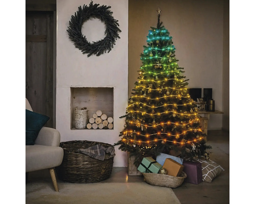 Sapin de Noël décoré avec guirlande lumineuse à côté d''une cheminée et d''une couronne
