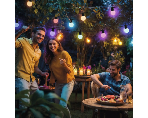 Eine Gruppe von Freunden feiert eine Party im Garten mit einer Lichterkette.