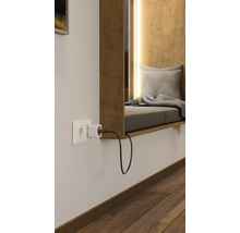 Steckdose mit Stecker in einem hellen Raum mit Fensterbank und Sitzgelegenheit.