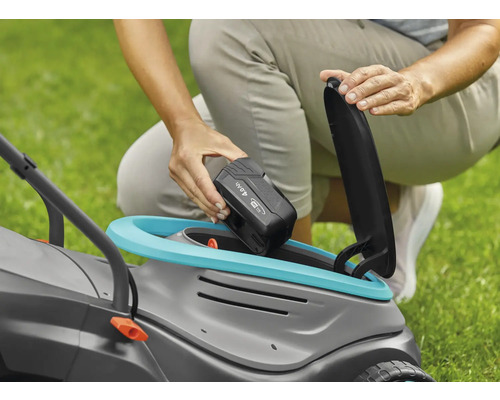 Eine Person setzt einen 4,0-Ah-Akku in einen Rasenmäher ein