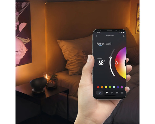 Un smartphone dans la main affiche une application pour contrôler une lampe de table dans une chambre.