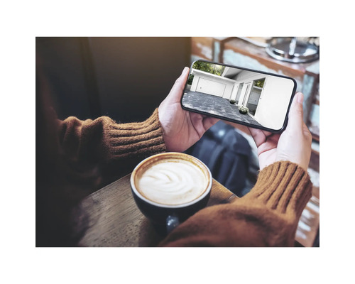 Personne tenant un smartphone avec vue sur un garage