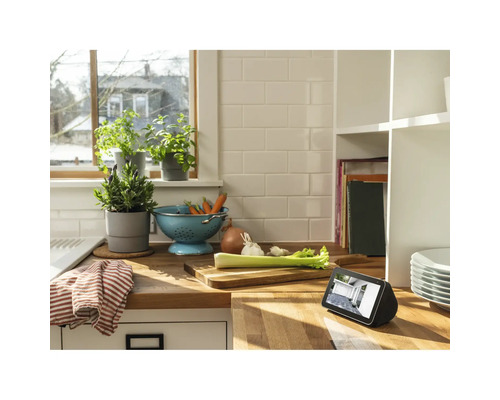 Scène de cuisine avec un bol de légumes, des pots d''herbes et un appareil numérique sur un plan de travail