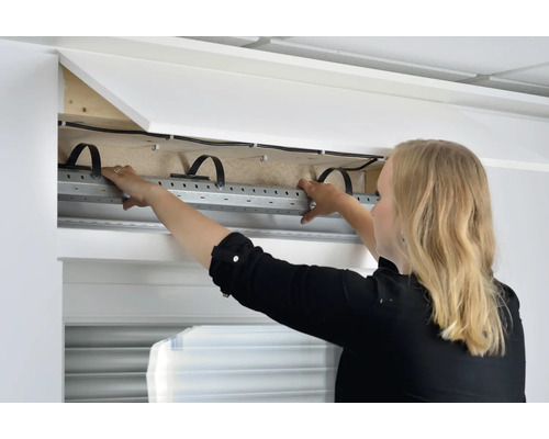 Femme monte un coffre de volet roulant