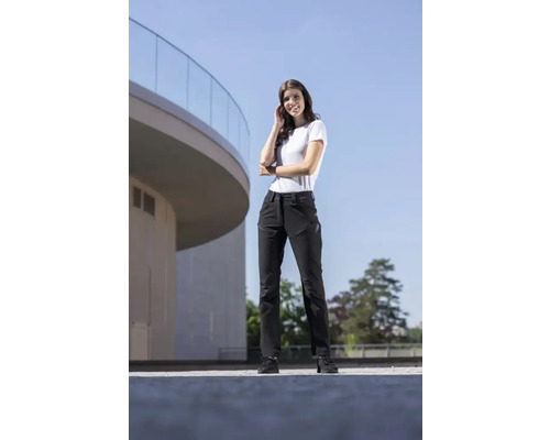 Une femme porte un pantalon de travail à l''extérieur devant un bâtiment.