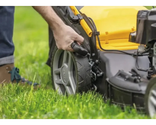 Une personne utilise une tondeuse à gazon sur une pelouse.