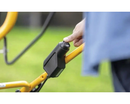 Gros plan d''une main actionnant un bouton de démarrage sur une tondeuse à gazon.