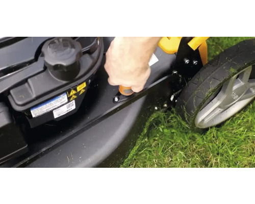 Gros plan d''une tondeuse à gazon sur de l''herbe dont la hauteur de coupe est en cours de réglage