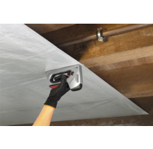 Une personne fixe un film à un plafond en bois avec une agrafeuse manuelle.