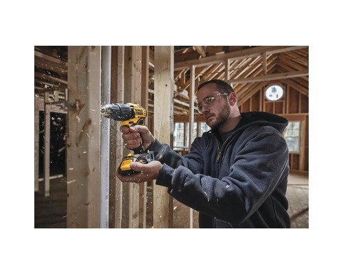 Handwerker bohrt mit einem Akku-Bohrschrauber von Dewalt in einem Rohbau Holz.