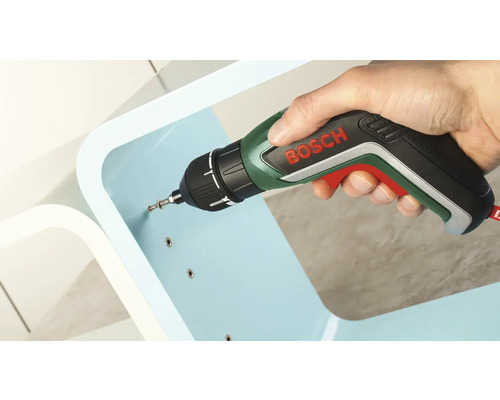 Une main visse une vis dans un meuble bleu clair à l''aide d''un tournevis sans fil Bosch