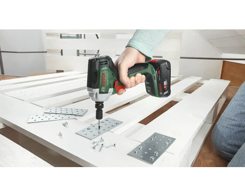 Eine Person verwendet einen Akku-Schlagschrauber zum Befestigen von Metallplatten an einer Palette mit Schrauben. Bosch Logo.