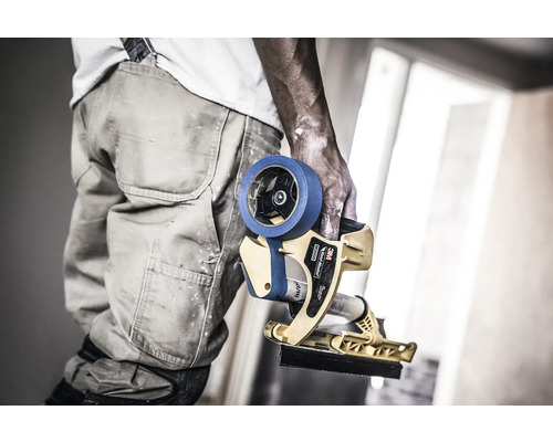 Un artisan tient un applicateur de ruban de masquage pour travaux de peinture