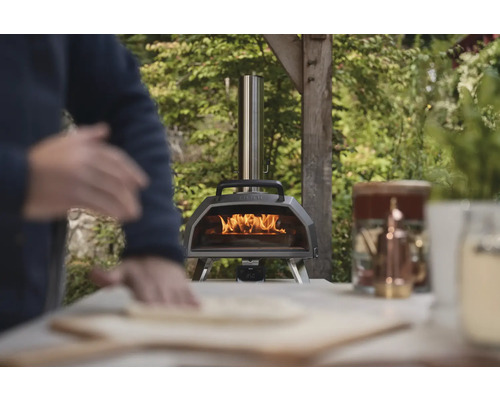 Four à pizza à bois avec opérateur préparant une pizza