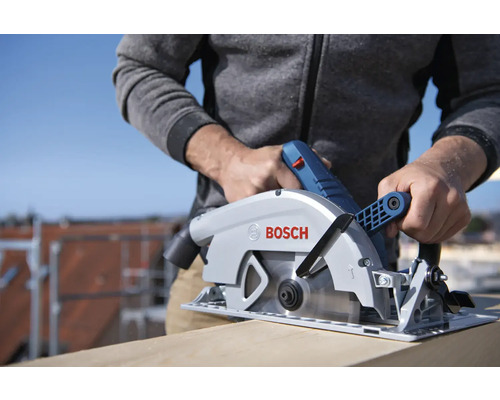 Un homme scie une planche de bois avec une scie plongeante Bosch