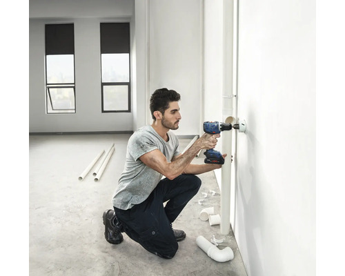 Artisan perçant un trou avec une perceuse-visseuse sans fil dans un mur pour l'installation d'une canalisation
