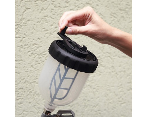 Farbspritzpistole mit Farbbehälter, der von einer Hand geöffnet wird