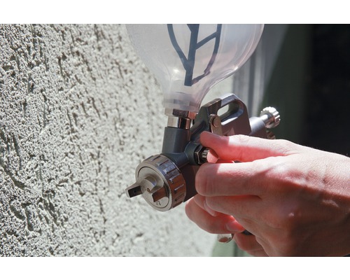 Spritzpistole beim Farbauftrag auf eine Wand.