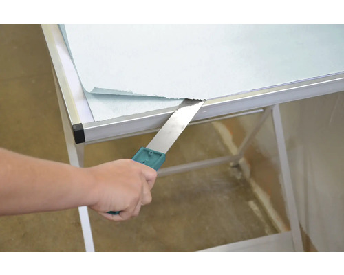 Spachtel entfernt Tapete von Tisch