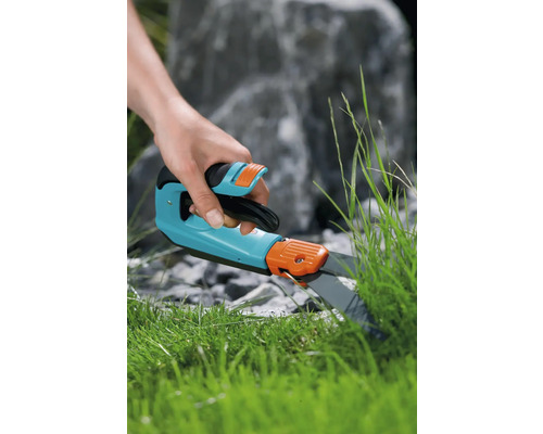 Eine Person schneidet Gras mit einer Rasenkantenschere.