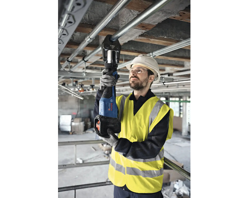 Artisan utilisant une pince à sertir pour sertir des tuyaux sur un chantier.