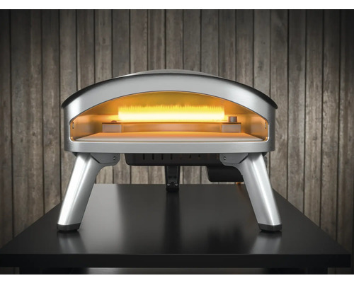 Four à pizza argenté sur une table avec chambre de cuisson ouverte