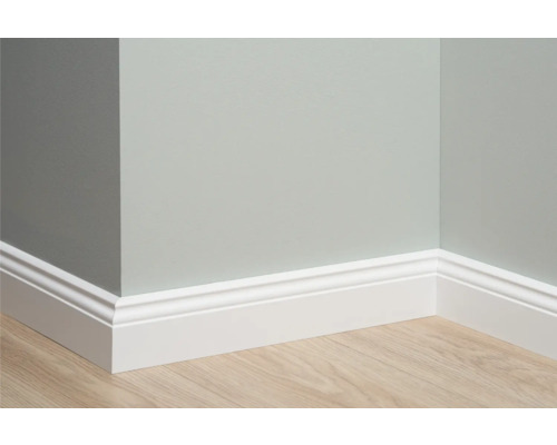 Coin de pièce avec plinthe blanche sur plancher en bois