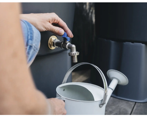 Person befüllt Gießkanne mit Wasser aus Regentonne