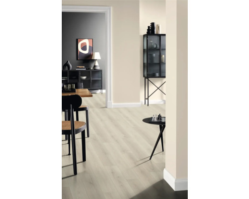 Innenraum mit hellem Laminatboden, Stühlen und Dekorationsgegenständen auf Tischen und in einem Glasschrank.