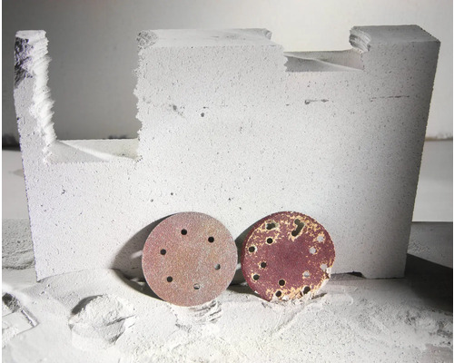 Zwei Schleifscheiben vor einem bearbeiteten Betonstein