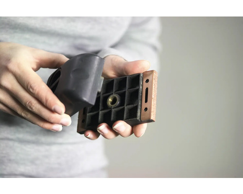 Eine Person hält eine Maschinenfußplatte und eine Maschinenfußkappe in der Hand.