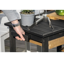 Table d''appoint noire avec plante, pince à grillade et tiroir coulissant.