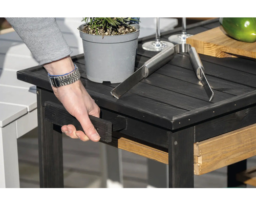 Table d''appoint noire avec plante, pince à grillade et tiroir coulissant.