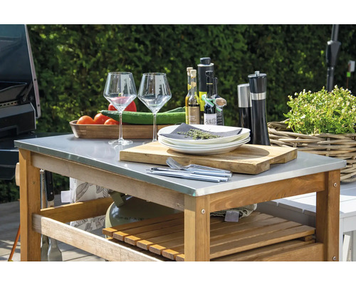 Table de barbecue avec vaisselle, verres, épices, huiles, planche à découper et légumes