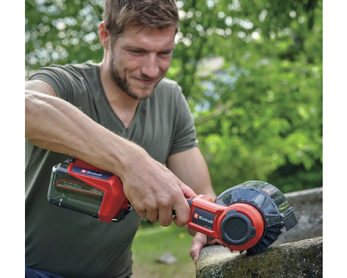Mann verwendet eine Akku-Fugenbürste von Einhell zur Reinigung einer Steinoberfläche.