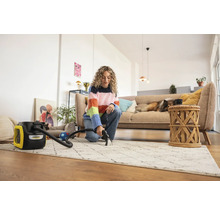 Femme nettoie un tapis avec un aspirateur-injecteur Kärcher dans un salon lumineux