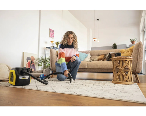 Femme nettoie un tapis avec un aspirateur-injecteur Kärcher dans un salon lumineux