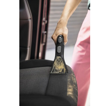 Gros plan d''une personne nettoyant un siège de voiture avec un détachant portable.