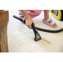 Nettoyeur de tapis en cours d''utilisation sur un tapis de couleur claire.