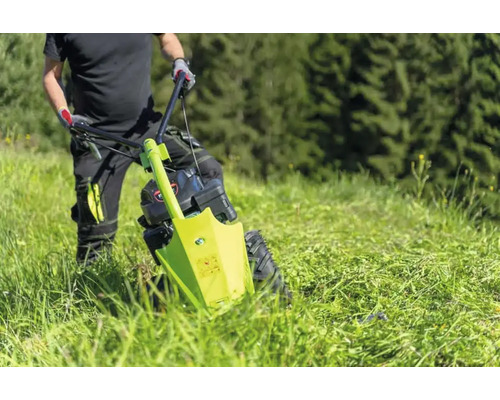 Un homme utilise une faucheuse à fléaux dans un pré.