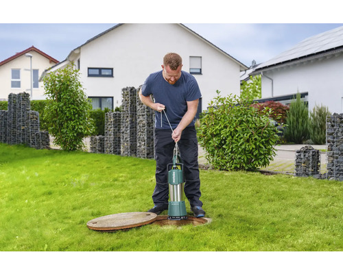Mann bedient eine Metabo Tauchpumpe auf einer Rasenfläche