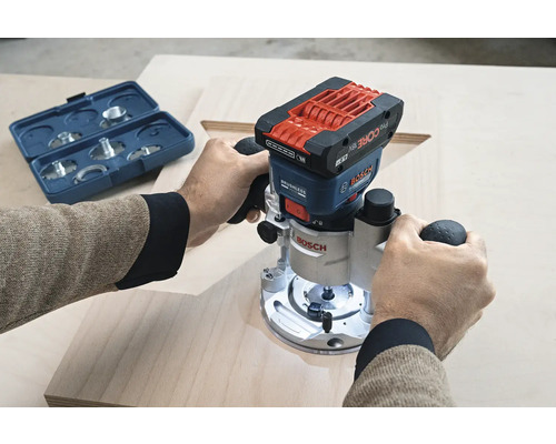 Une personne utilise une défonceuse à batterie Bosch sur une planche de bois, avec une boîte à outils bleue en arrière-plan.