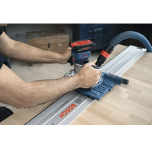 Une personne utilise une défonceuse à batterie avec rail de guidage de Bosch sur une pièce.