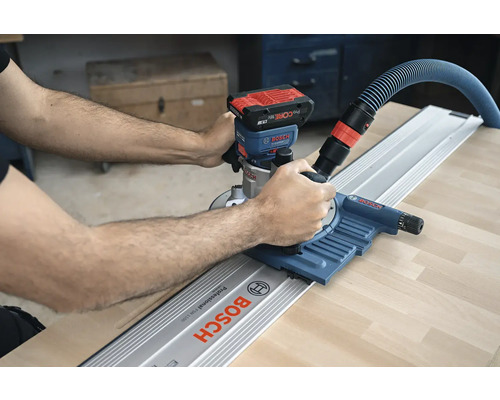 Une personne utilise une défonceuse à batterie avec rail de guidage de Bosch sur une pièce.