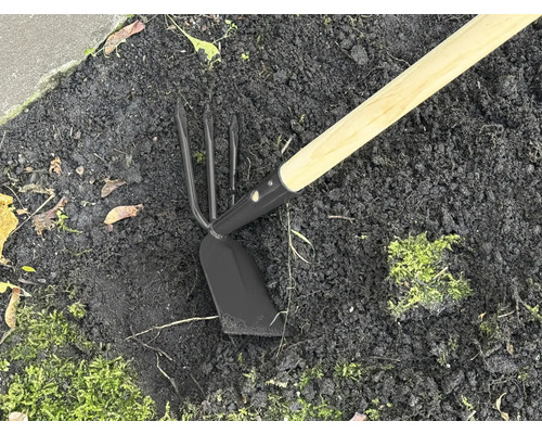 Gartengerät mit Holzstiel und Metallkopf im Erdreich