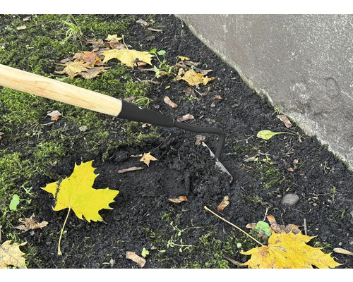 Nahaufnahme einer Hacke mit Holzgriff im Gartenboden.