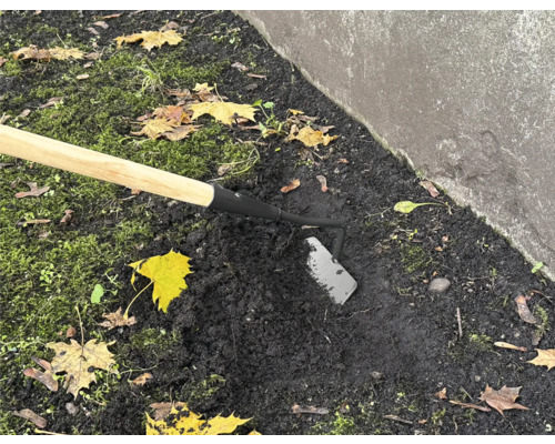 Gartenhacke mit Holzstiel im Einsatz im Gartenboden.