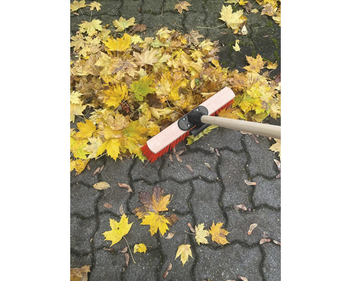 Laubbesen auf Pflastersteinen mit Herbstlaub